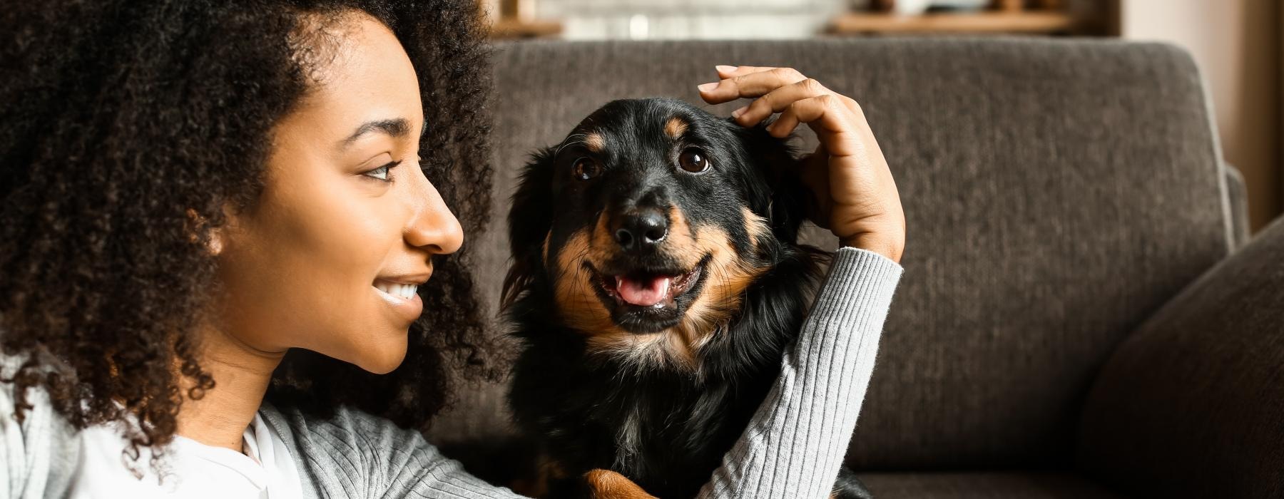 woman pets her dog on a couch